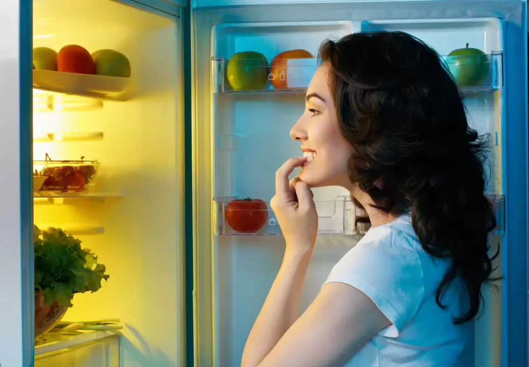 gadis melihat ke dalam lemari es selama penurunan berat badan yang cepat